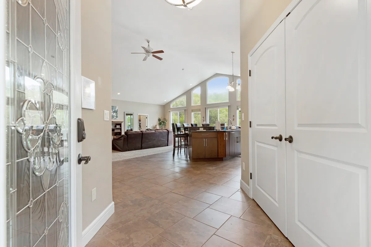 A spacious living area with a kitchen island, large windows letting in natural light, and comfortable seating ideal for gatherings. The scene is warm, inviting, and meticulously arranged, perfect for welcoming guests of all ages.