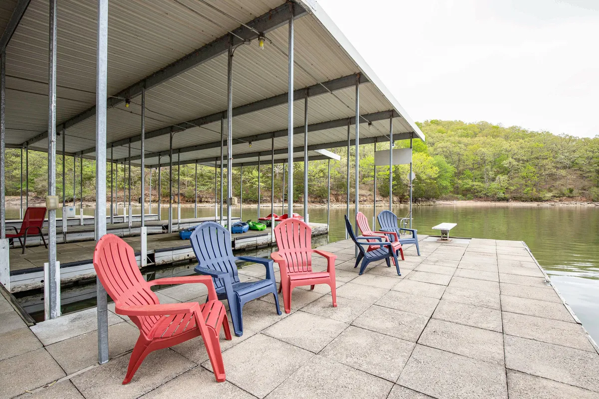 A close-up of a dock featuring classic red and blue Adirondack chairs overlooking the sparkling water. The dock is spacious and ready for both relaxation and activity, emphasizing the exclusive, private nature of the lake experience.
