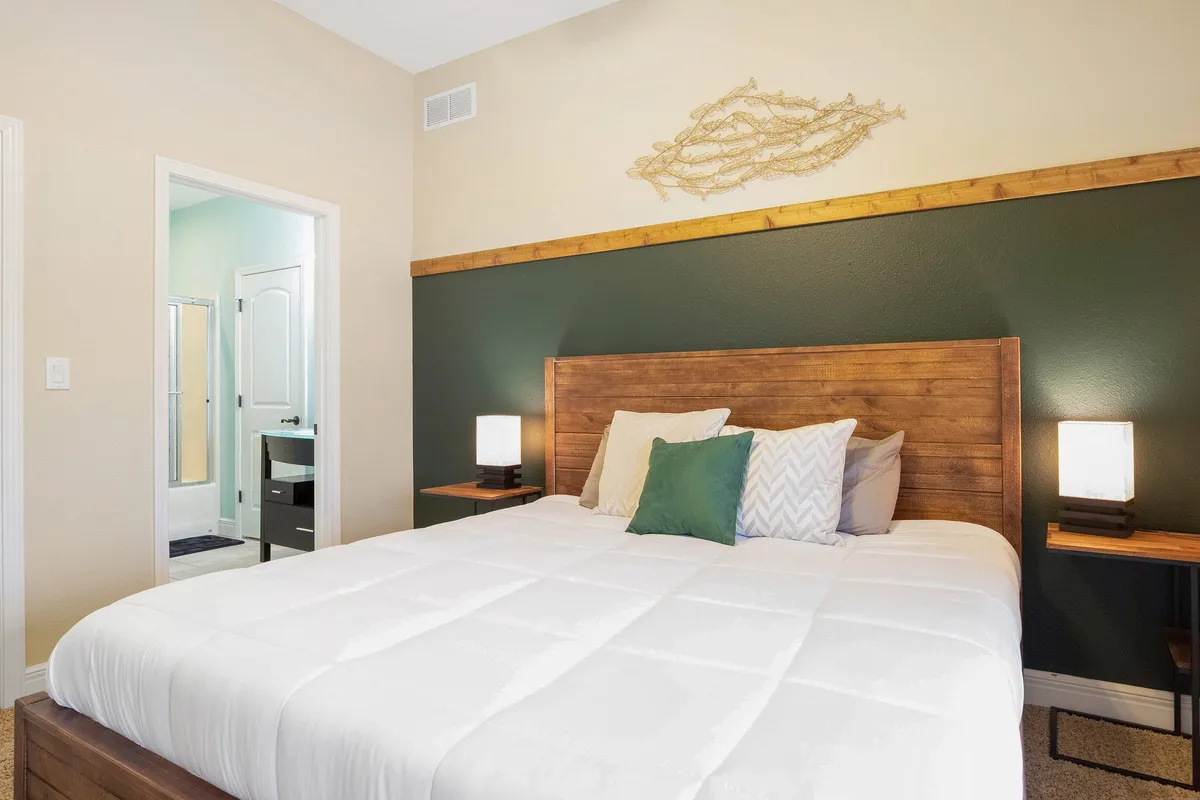 A peaceful bedroom featuring a large, comfortable bed with decorative wall art and matching nightstands. The mood is tranquil and inviting, emphasizing comfort and privacy.