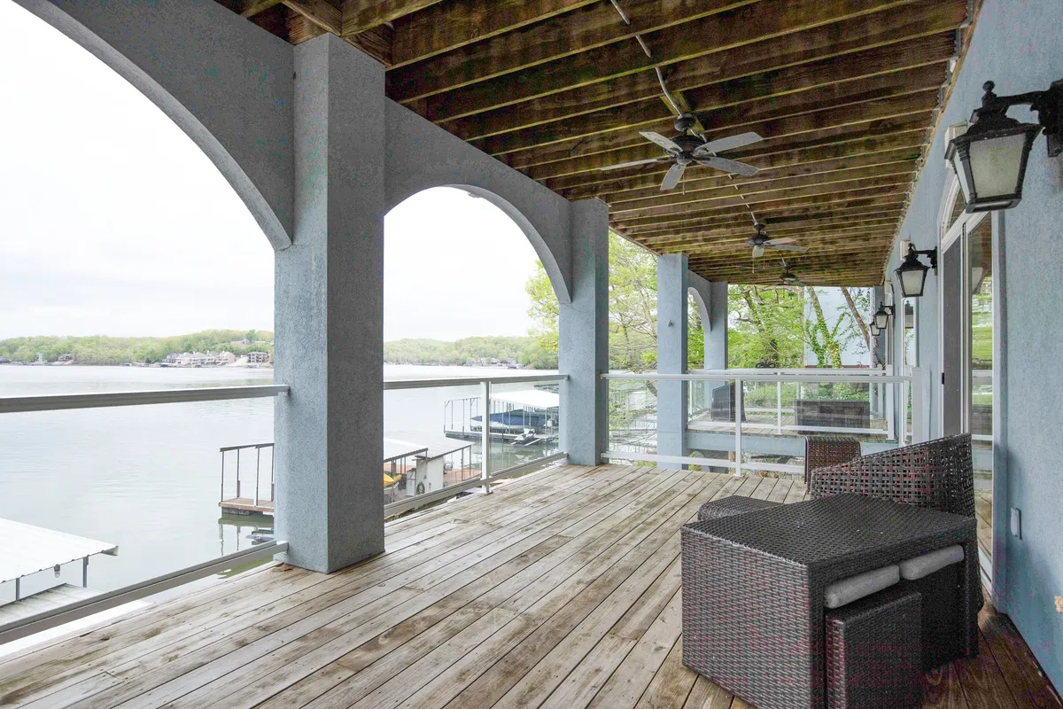 A serene deck scene with outdoor seating, sturdy columns, and a wide lake view. The spacious wooden deck invites relaxation, social gatherings, and outdoor dining while overlooking the shimmering water, perfect for catching sunrises and sunsets.