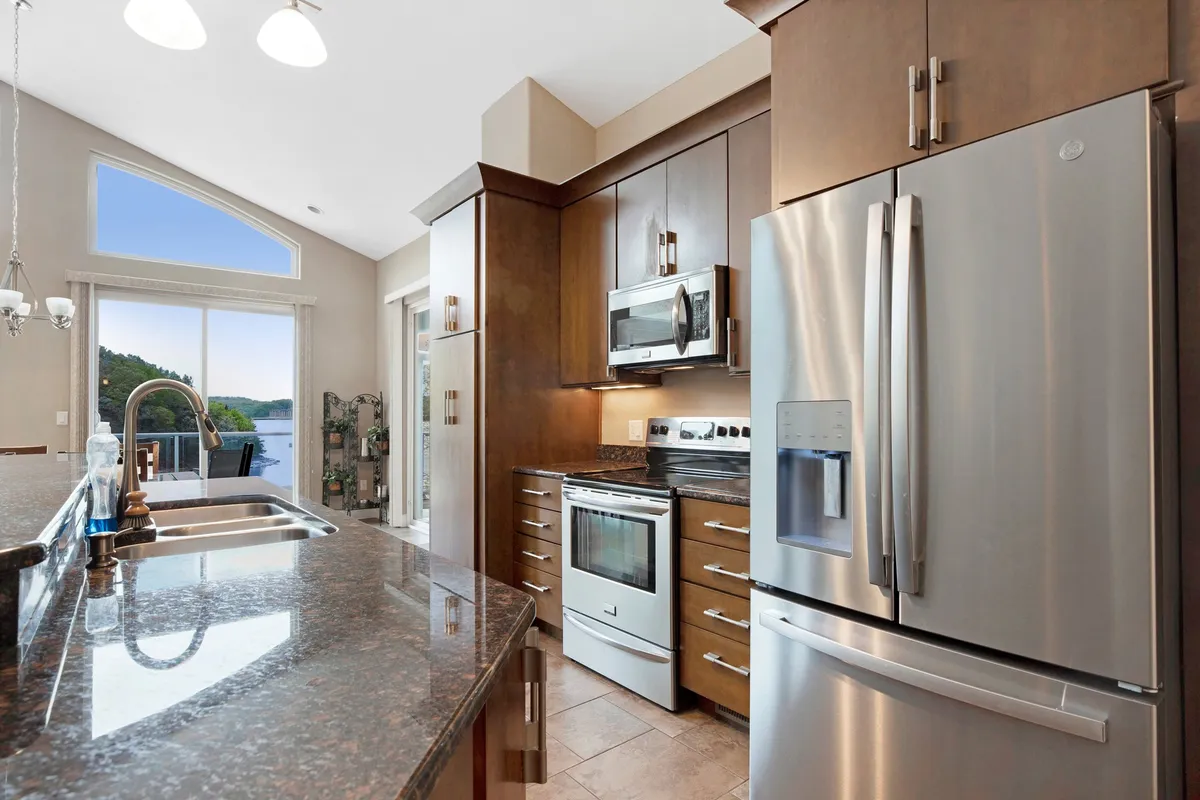 A modern kitchen with granite countertops, stainless steel appliances, and large windows providing scenic water views. The room is bright, stylish, and inviting—ideal for both preparing meals and socializing.