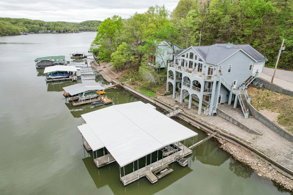 A wide shot of the property’s lakefront exterior, highlighting the dock, the large house, lush greenery, and ample space for families and friends to gather. The image emphasizes both the scale of the home and the inviting outdoor areas designed for larger groups.